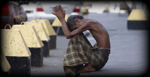 Homeless man sits on side of a street in the port city of Aden